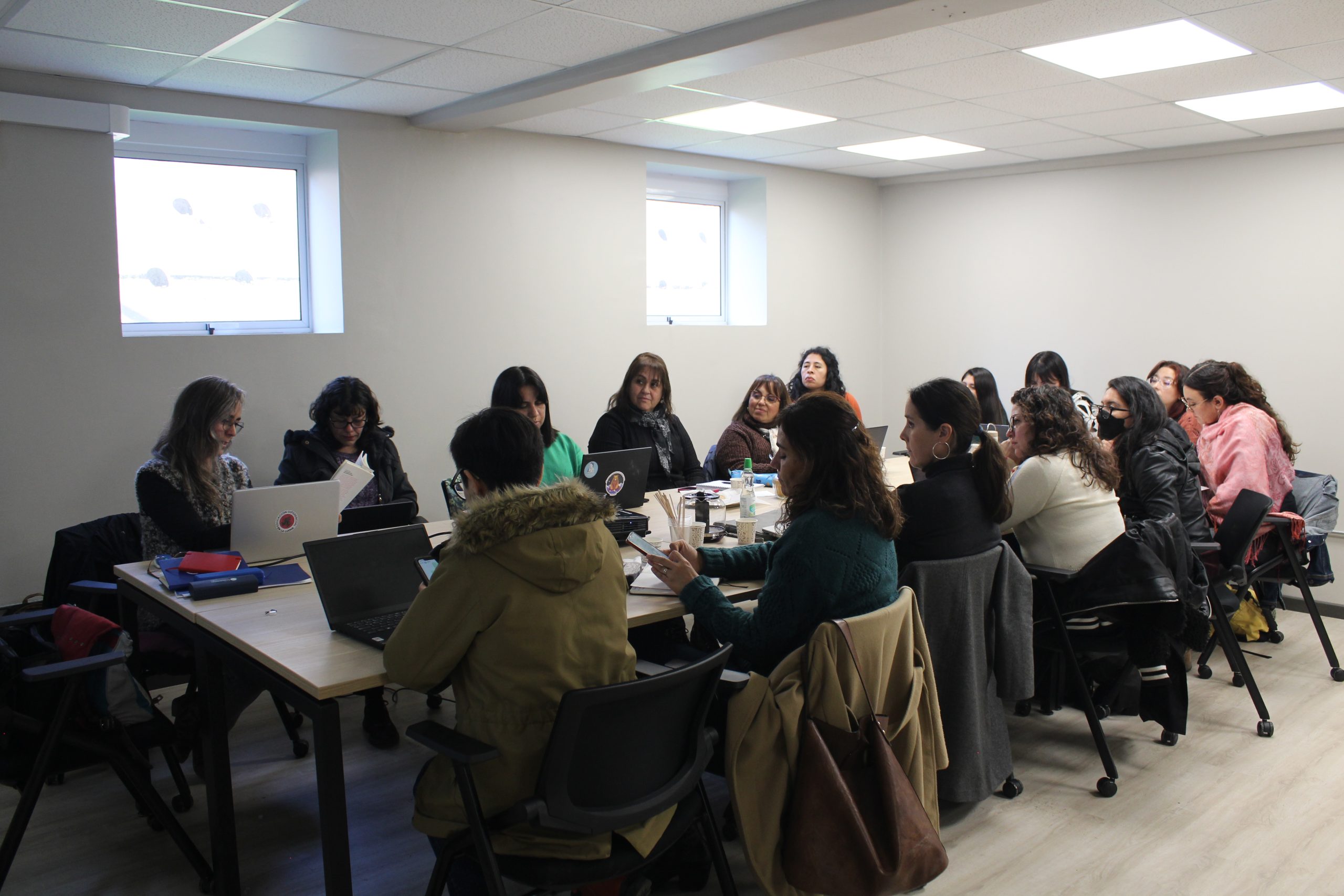 Fotografía de académicas sentadas en una mesa mirándose, durante el taller para guiar a académicas e investigadoras de la UMCE